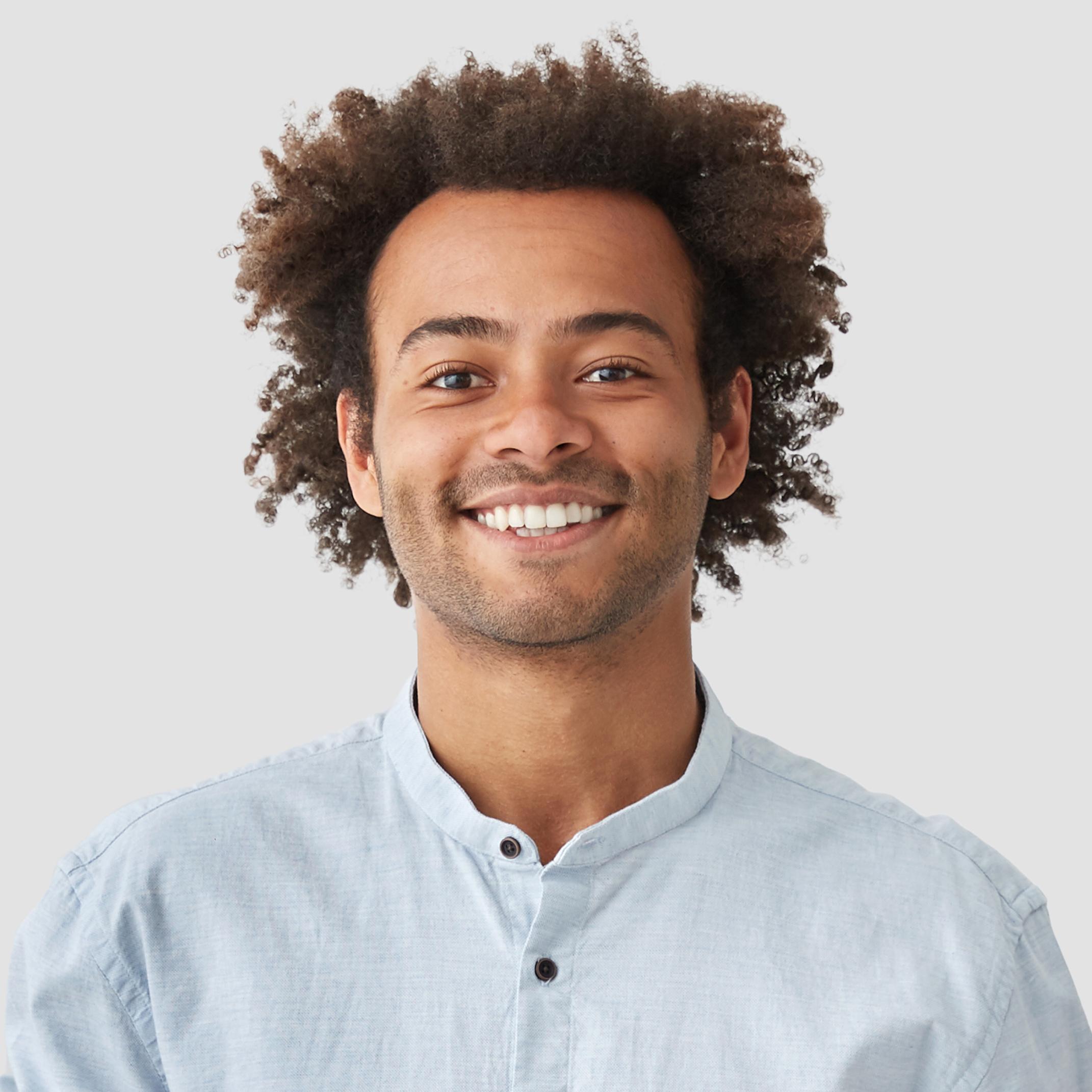 Attractive mixed race male with positive smile, shows white teeth, keeps hands on stomach, being in high spirit, wears white shirt, rejoices positive moments in life. People and emotions concept